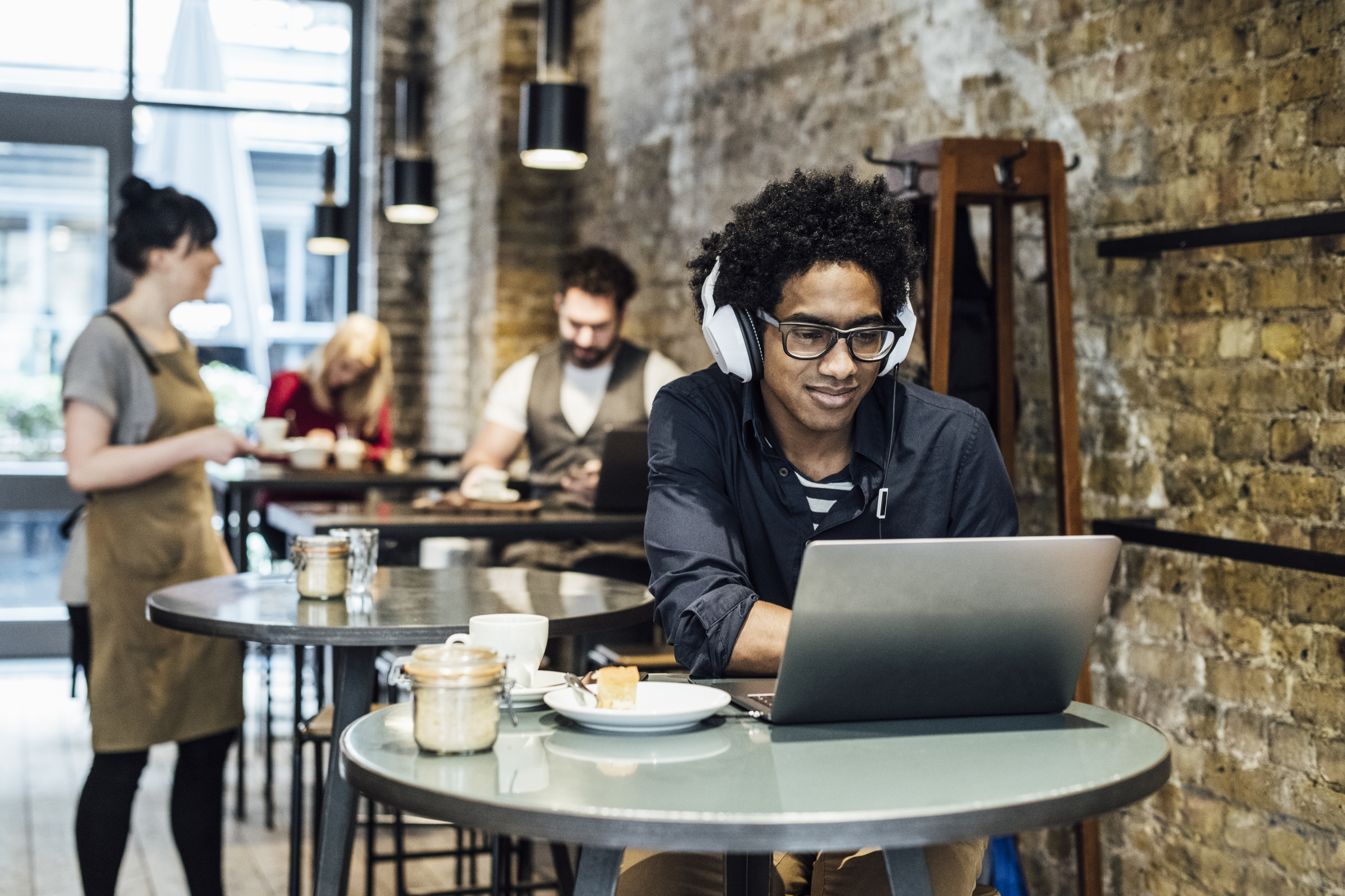 man in coffee shop on laptop listening to music